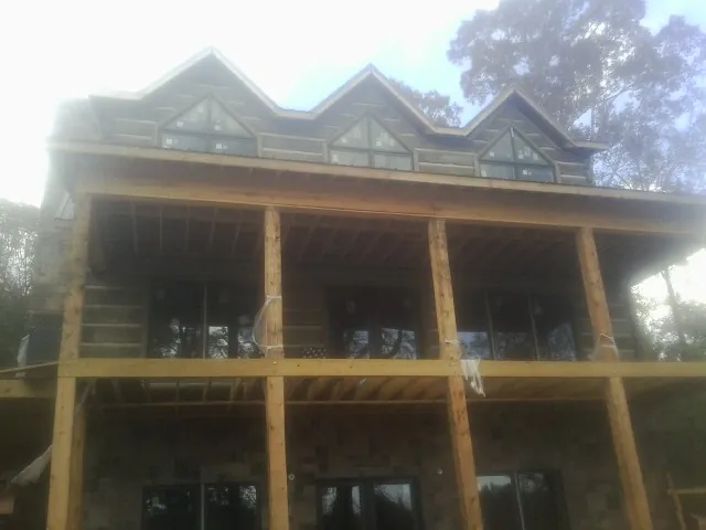 Dormers and porch framing on a large log home under construction — Roof Coating work by our crew in West Point